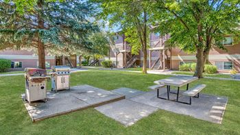 a picnic area with a grill and picnic table in front of a house